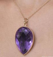Pear-shape amethyst pendant on chain against skin