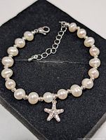 Full bracelet laid out showing pearls, spacers, clasp, extender chain and starfish charm