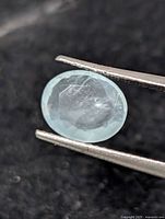 Close-up of oval aquamarine held by tweezers