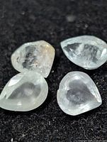 Four pear-cut aquamarine gemstones on black background