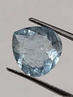 Front view of the loose faceted aquamarine held by tweezers