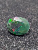 Oblique view of oval faceted black opal showing colour play