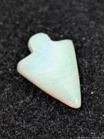 Front view of carved opal showing arrowhead shape and color play