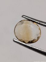Oval faceted citrine held by tweezers