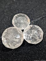 Three round faceted clear quartz stones on black background