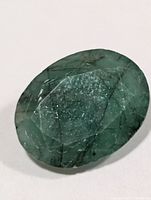 Front view of oval emerald showing faceted surface and inclusions