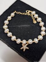 Bracelet laid flat showing pearls, gold beads and starfish charm