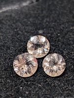 Three round faceted morganite stones on black background