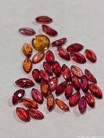 Group of marquise red-orange and one round yellow-orange sapphire on white background