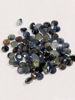 Pile of small round faceted sapphires on white background