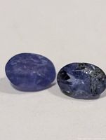 Two loose oval tanzanite gemstones on white background