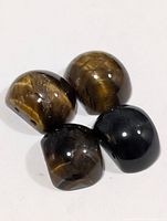 Four polished tiger eye beads showing color and drill holes