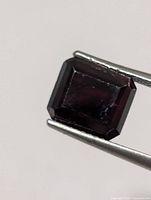 Rectangular emerald-cut tourmaline held by tweezers