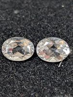 Two loose oval white topaz gemstones on black background
