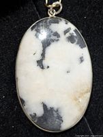 front view of oval white and black stone pendant in silver bezel