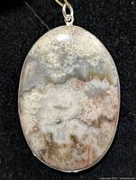 Front view of oval crazy lace agate pendant in silver bezel