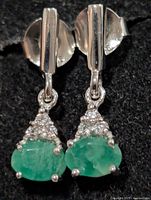 Front view of earrings showing emeralds and clear stones