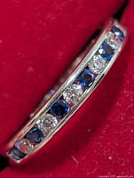 Close-up of silver ring showing alternating blue and clear stones