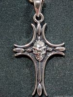 Front view of silver cross pendant with skull
