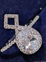 Front view of sterling silver CZ ring showing pear center stone, halo and square accent