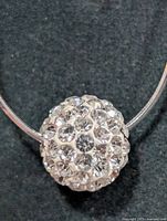 Close-up of larger pavé crystal ball pendant on silver wire necklace