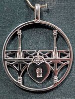 Front view of round silver pendant showing bridge design and heart padlock charm