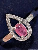 Front view of silver ring showing ruby and surrounding CZ halo