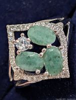 Front view showing emerald cabochons, centre CZ, pavé halo