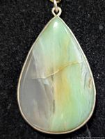 Front view of pear-shaped opalized petrified wood pendant in silver bezel
