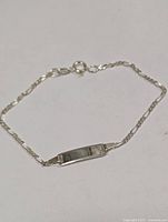 Top view of silver chain bracelet with ID plate and clasp