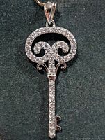 Front view of key-shaped silver pendant with pave CZ