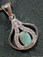 Front view of silver pendant showing emerald and CZ halo
