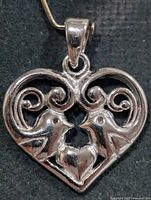 Front view of heart pendant showing birds and scrollwork