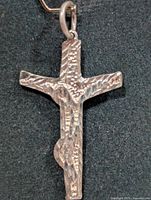 Front view of textured silver cross pendant with bail