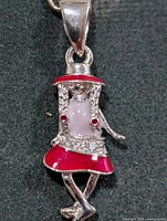 Front view of silver girl pendant showing red enamel hat and skirt, pink torso and rhinestones