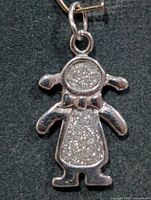 Front view of silver figurine pendant showing textured inlay and jump ring