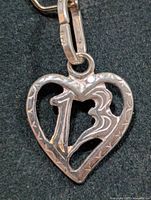 Front view of silver heart pendant showing cut-out 13 design