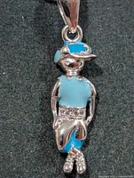 Front view of silver-tone boy figure pendant with blue enamel