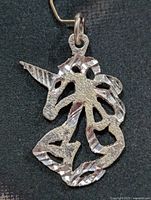 Front view of silver unicorn silhouette pendant showing texture and cut-out design