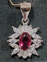 Front view of pendant showing ruby-tone center stone and CZ halo