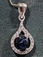 Front view of silver pendant showing sapphire centre and CZ halo