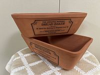 Two terracotta Henry Watson bread baker pans stacked showing shape and lettering