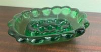Side view of green glass flower frog bowl showing ruffled rim and pebbled texture