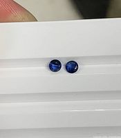 Two round royal blue sapphires on white background