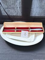 Two white platters stacked with Gerber sharpener in wood case on top