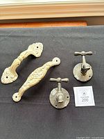 Two ornate cream handles and two grey tap valves on black surface