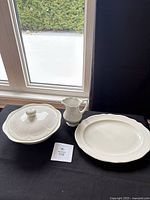 Serving plate, covered bowl with lid and creamer on table