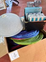 Box showing stacked folded paper lanterns, metal frames, decorative lights