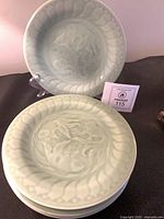 Stack of four celadon koi plates, top plate on stand