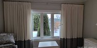 Both curtain panels hanging on window showing off-white and grey design